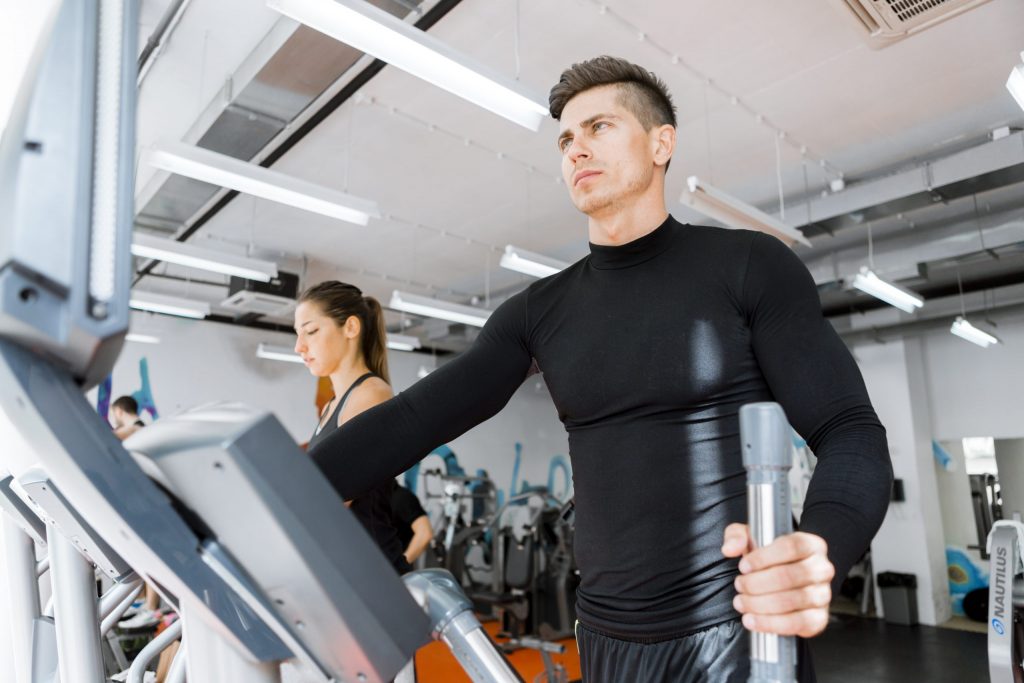 Young healthy group of people working out on a elliptic trainer in a fitness center